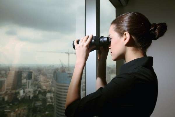 Business woman searching with binos through a large window for How To Get Quality Blog Content