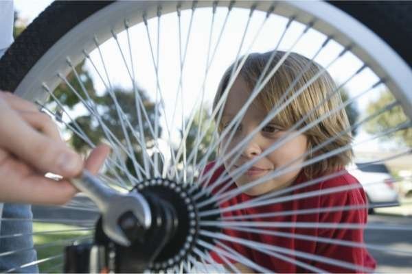 child looking through the spokes and wheels of a bicycle wheel